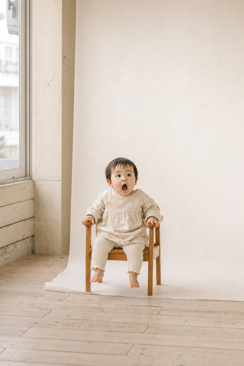 小さな木の椅子に座って目を丸くする赤ちゃん（掲載イメージ）