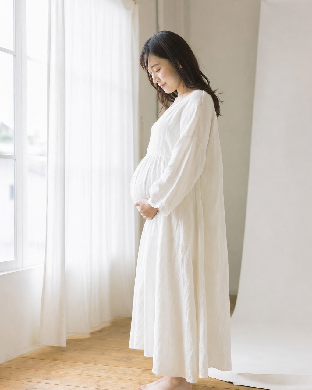 窓辺でおなかに手を添えて立つ女性（掲載イメージ）