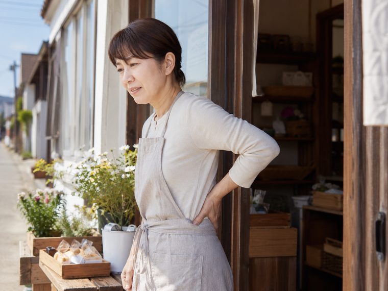 立ち仕事で腰に手を当てる女性